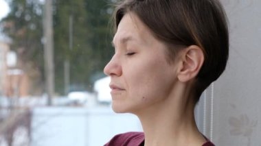 Depresyondaki endişeli genç kadın sorun için üzülüyor. Üzgün kızın yansıması, pencereden bakıp zihinsel stres kavramını düşünmesi. Yan yüzünü kapat.