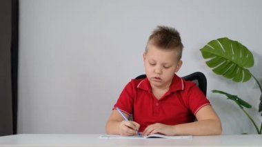 Okul çocuğu ev ödevini yapıyor ve uykulu ve sıkkın hissediyor.