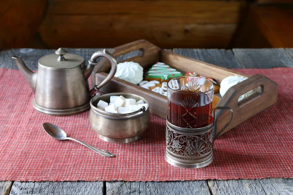 一只红茶放在木制桌子上 桌子上摆放着银器和一个盘子 盘子里有姜饼饼干和棉花糖 — 图库照片