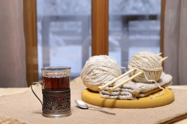 一杯茶 羊毛线和针织在窗前的桌子上 背景是冬季的风景 — 图库照片