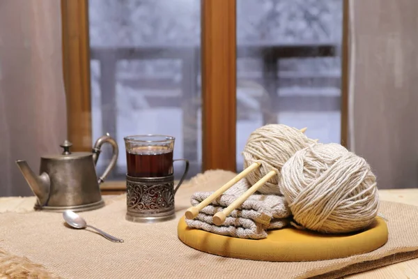 毛线和毛线 一杯茶放在窗前的桌子上 背景是冬季的风景 — 图库照片