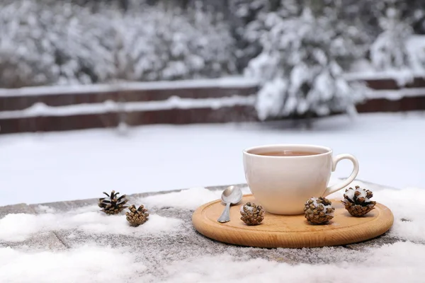 White Mug Hot Tea Pinecones Snowy Wooden Table Background Winter — Zdjęcie stockowe