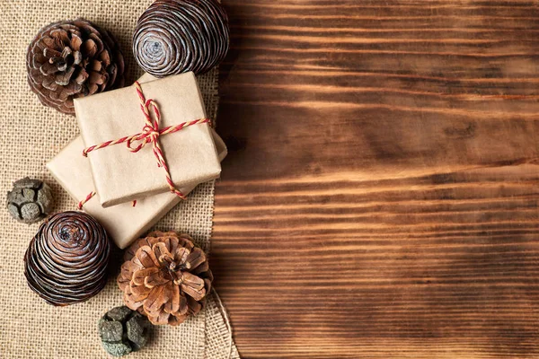 Christmas Flatlay of pine cones and gift boxes on wooden background with copy space