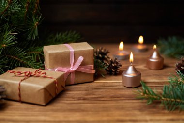 Arka planda yanan mumların, köknar dallarının ve konilerin olduğu Noel hediyesi kutusu