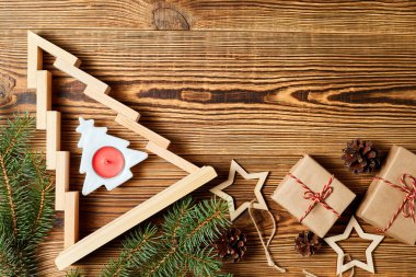 Tahta Noel ağacı hediye kutuları, köknar dalları, çam kozalakları ve ahşap arka planda tahta yıldızlar.
