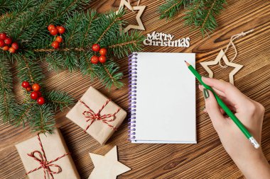 Kız gelecek yıl için bir dilek listesi hazırlayacak. Yılbaşı aksesuarlarının arka planına karşı.