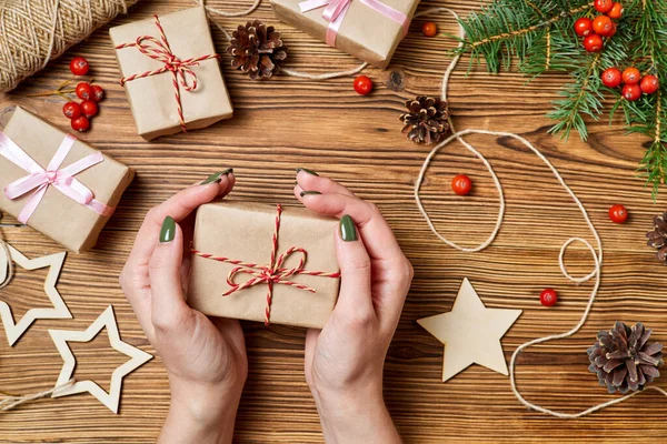 The girl holds in her hand a gift box on the background of christmas accessories