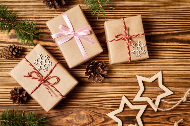 Noel hediye kutuları ahşap arka planda çam kozalakları, köknar dalları ve yıldızlarla