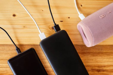 Powerbank akıllı telefonu ve taşınabilir hoparlörü USB kullanarak şarj ediyor. Yakın çekim, seçici odaklanma