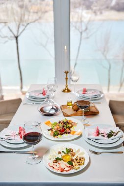 Kırmızı şarap ve aperatif dolu dekore edilmiş bir restoran masası misafirleri bekliyor. Yakın plan.