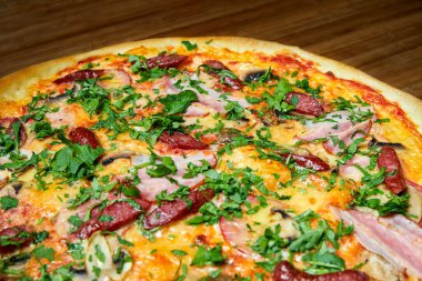 Peynirli pizza, domuz pastırması ve ahşap tabakta otlar. Yakın çekim, seçici odaklanma