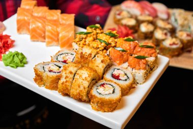 Garson elinde beyaz bir tabakta suşi rulosu tutuyor. Yakın çekim, seçici odaklanma