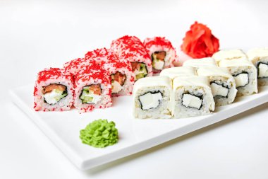 Beyaz bir tabakta somon, salatalık, peynir ve wasabi ruloları.