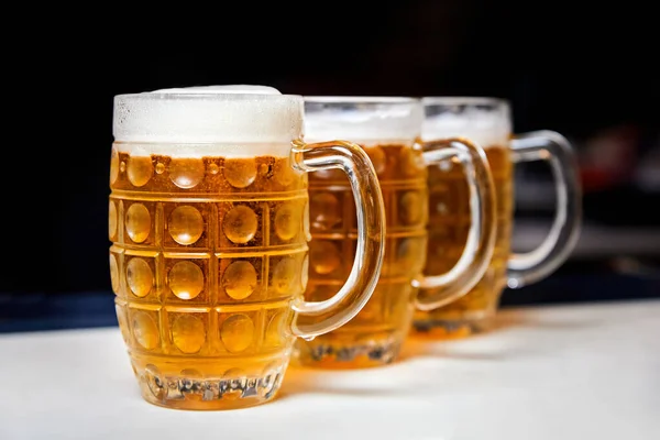 Tezgahta üç bardak taze köpüklü bira.