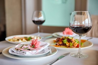 Kırmızı şarap ve aperatiflerle servis edilen bir restoran masası misafirleri bekliyor. Yakın çekim, seçici odaklanma