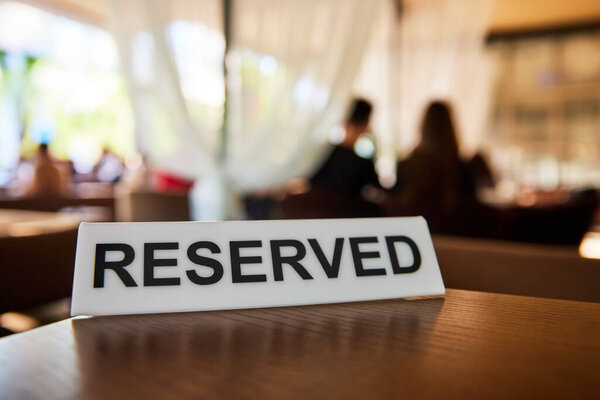 Пластиковая табличка с надписью Зарезервировано на столе ресторана