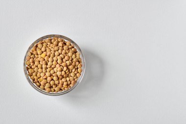 Beyaz zemin üzerinde şeffaf cam plaka içinde çiğ mercimek taneleri. Yakın çekim, kopyalama alanı, üst görünüm