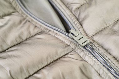 Metal fermuarın kayganlaştırıcısı açık zeytin rengi ceketin üzerine metal çekiçle bağlanmış.