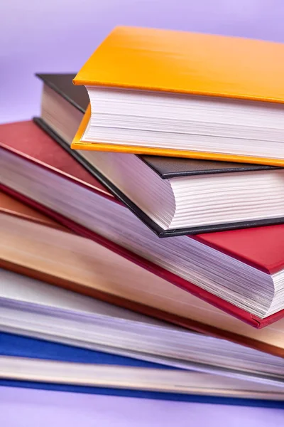 Stack of colorful books on purple background