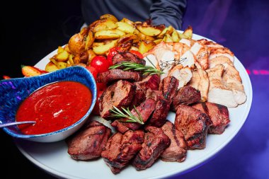 Domuz eti ve fırında patates, domates ve soslu tavuk kebabı.