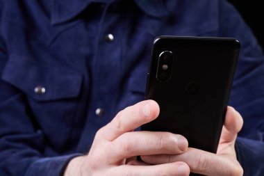 Koyu arkaplanda akıllı telefon ekranına bakan adam