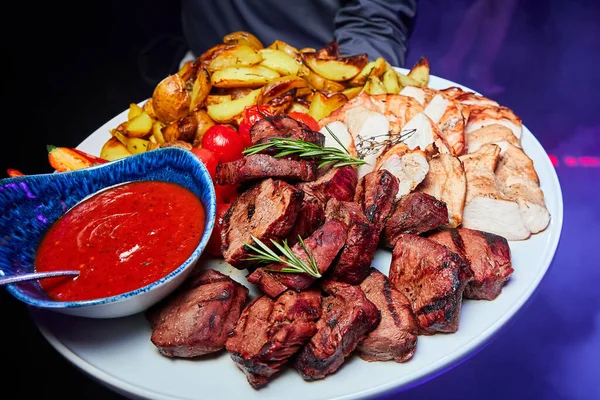 Domuz eti ve fırında patates, domates ve soslu tavuk kebabı.