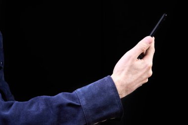 Koyu arkaplanda akıllı telefon ekranına bakan adam