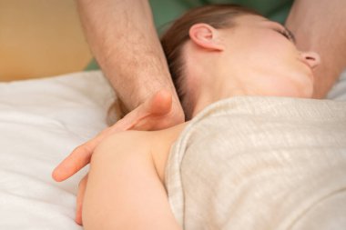 Beyaz kadın spa salonunda omzuna masaj yaptırıyor.