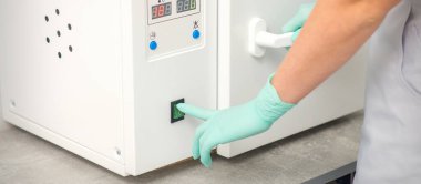 Koruyucu eldivenli güzellik uzmanı, depilasyon prosedüründen önce aletleri dezenfekte etmek için makineyi çalıştırıyor