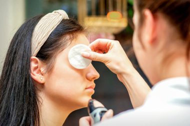 Makyaj sanatçısı genç bir kadının yüzünde profesyonel makyaj yapıyor.