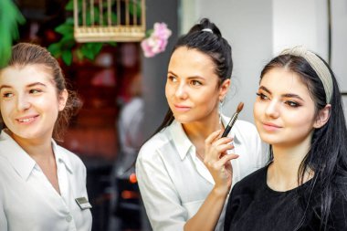 Makyaj sanatçısı, genç ve güzel geline makyaj yapıyor. Bir güzellik salonunda düğün makyajı yapıyor.