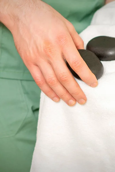 Närbild Massör Hand Torkar Svarta Massage Stenar Med Vit Handduk — Stockfoto