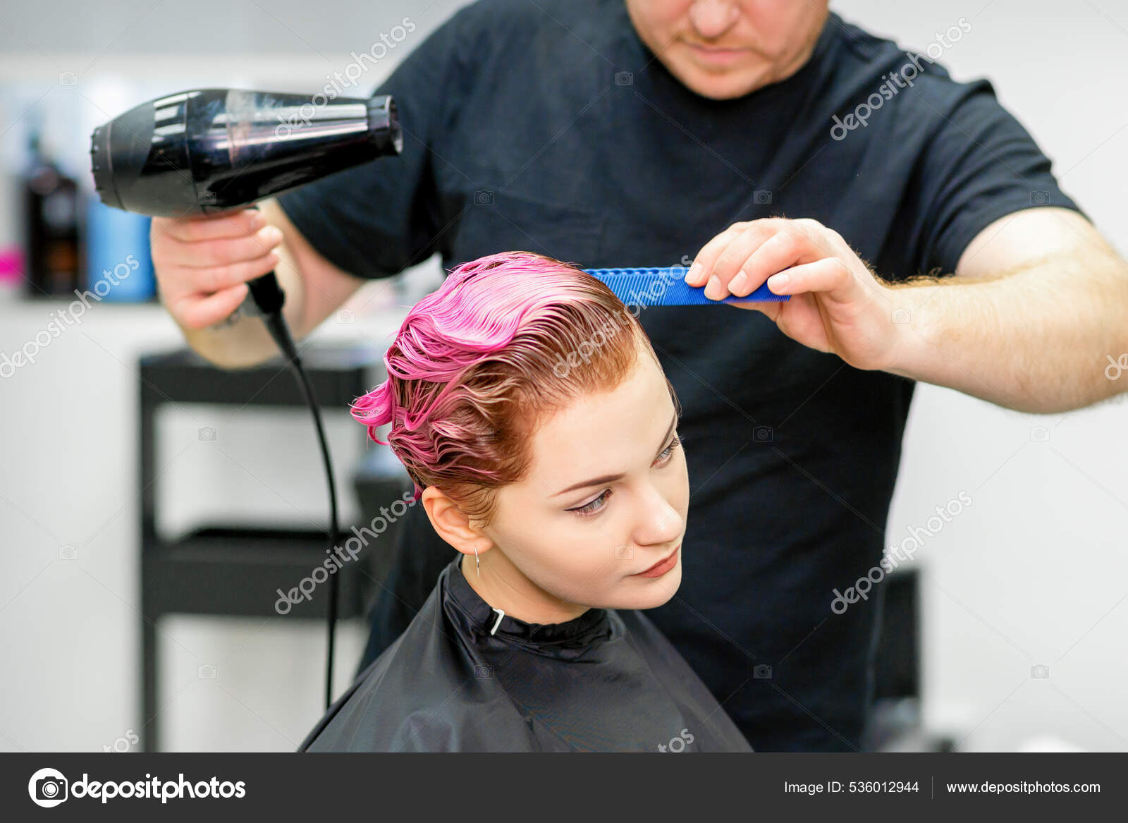 Cabeleireiro seca e modela o cabelo com um secador de cabelo no salão de  beleza