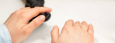 Manikür ustasının yaklaşması genç bir kadının ellerini manikür prosedürlerine hazırlar.