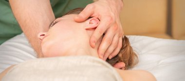 Osteopath rehabilitasyon kliniğinde kadın kafasına masaj yapıyor.