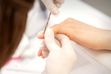 Manikür ustasına manikür makasıyla yakın çekim bir güzellik salonunda kadın tırnaklarının tırnaklarını kesiyor.