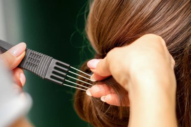 Kapalı kuaför kuaförü kuaförde genç bir kadın için saç stili yapıyor.