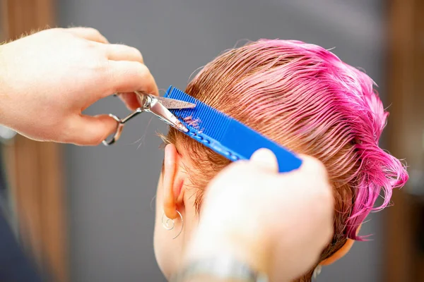 プロのヘアスタイリストがヘアサロンではさみで短いピンクの髪を切っています閉じる — ストック写真