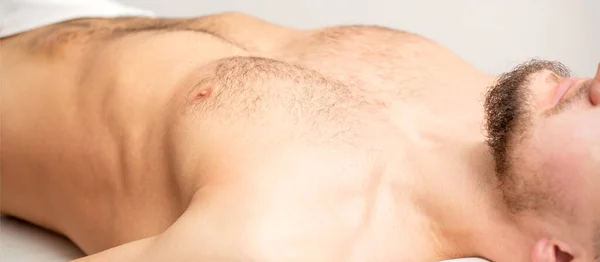 Hairy body, stomach, and chest of a man lying before epilation