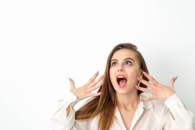 Ağzı açık genç beyaz bir kadın beyaz arka planda saklanıp şaşkınlığını dile getiriyor. Güzel sürpriz esmer kadın stüdyoda.