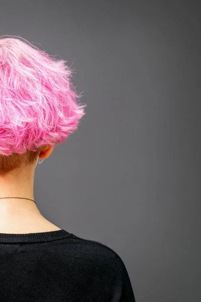 女性后脑勺 有卷曲的短粉色头发 背对着深色背景 — 图库照片