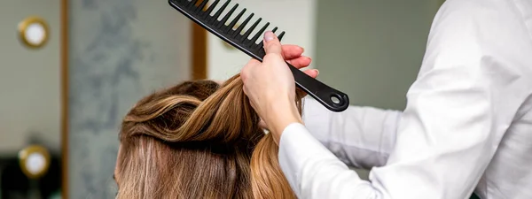 Μια Κομμώτρια Χτενίζει Μακριά Καστανά Μαλλιά Μιας Νεαρής Γυναίκας Ένα — Φωτογραφία Αρχείου