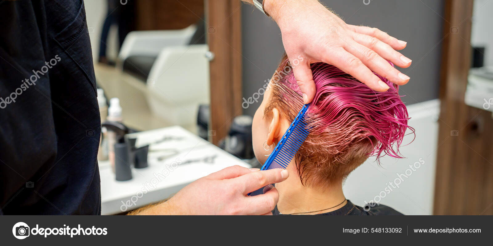 Secador de cabelo preto na mão de uma mulher em um fundo rosa