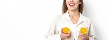 Beyaz arka planda iki parça portakal ve fotokopi alanı olan neşeli ve çekici genç bir kadın.