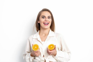 Beyaz arka planda iki parça portakal ve fotokopi alanı olan neşeli ve çekici genç bir kadın.