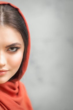 Gri arka planda kırmızı başörtüsü takmış güzel beyaz bir kadının portresi.