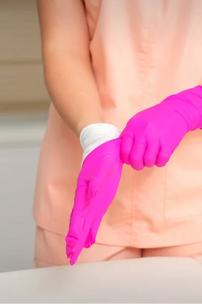 美容师的手戴上无菌的粉色手套 准备在室内迎接客人 — 图库照片
