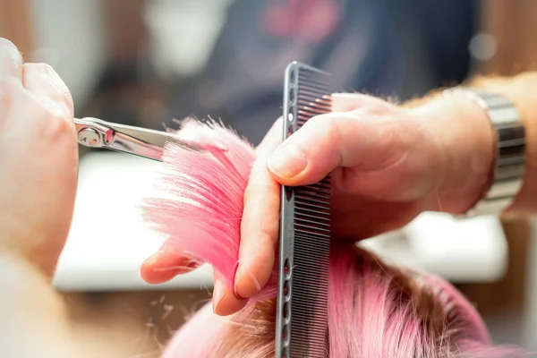 有新发型的女人男发型师用剪子在发廊剪粉色头发 — 图库照片