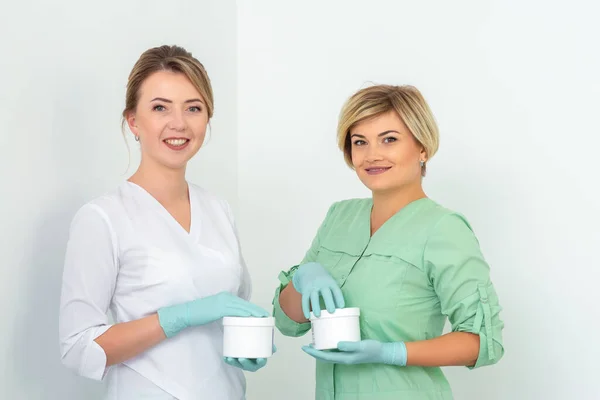Dois Cosmeticians Com Jarros Cera Depilação Que Sorri Contra Fundo — Fotografia de Stock