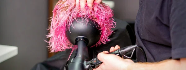 在美容院里 发型师用吹风机吹制湿透的定制粉色头发的发式 — 图库照片